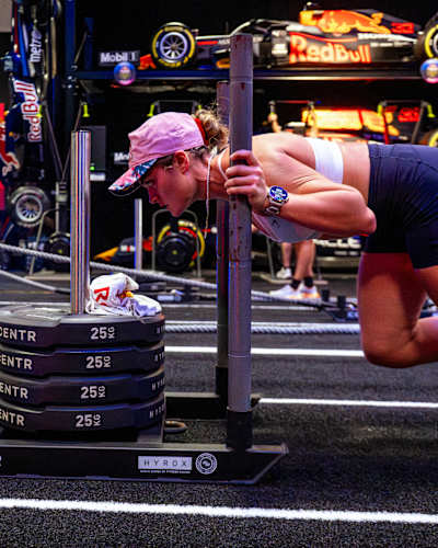 Athletes power through a strength challenge, pushing 100kg, at the Red Bull HYROX Coaches Camp in Silverstone Circuit, UK, with Red Bull Racing cars setting the scene in August, 2025.