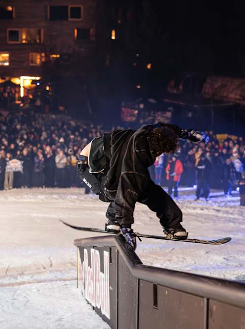 Un concurrent dynamique grille le rail lors du Red Bull Rail Riot 2026 à Laax, en Suisse, faisant vibrer la foule rassemblée pour cet événement de sports d'hiver électrisant