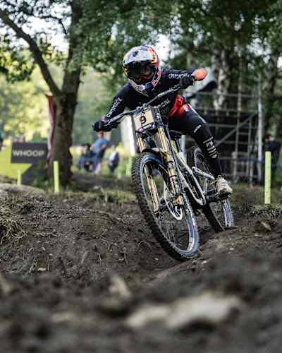 Myriam Nicole competes at the UCI Downhill Mountain Bike World Cup 2024 event in Loudenvielle, France, showcasing her skills on a rugged, muddy course amid lush greenery