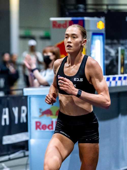 Joanna Wietrzyk, atleta profissional e recordista do HYROX, a passar por uma bancada com Red Bull 