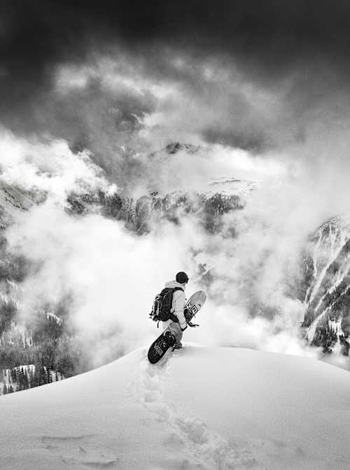 Snowboarder overlooking a snowy mountain panorama.