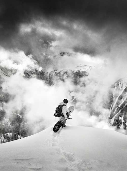 Snowboarder overlooking a snowy mountain panorama.