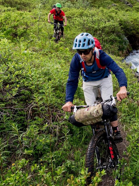 Kevin Murphy and Eric Porter ride singletrack next to a river during their Alaska MTB Exploration