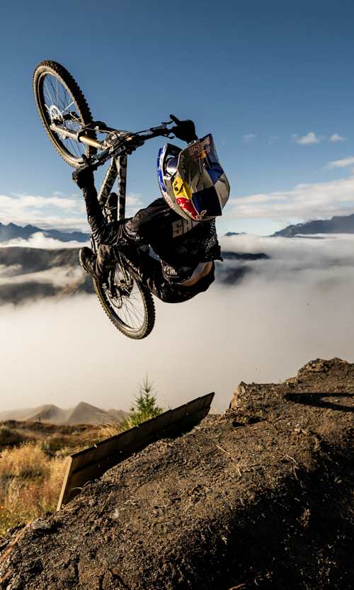 On February 14, 2026, Juan Diego Salido rides in the Red Bull Natural Selection Tour Bike event, performing a gravity-defying stunt in Queenstown, New Zealand against dramatic mountain backdrops