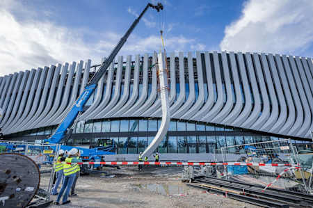 Ein Baukran hebt eine Lisene auf die Außenfassade des SAP Garden.