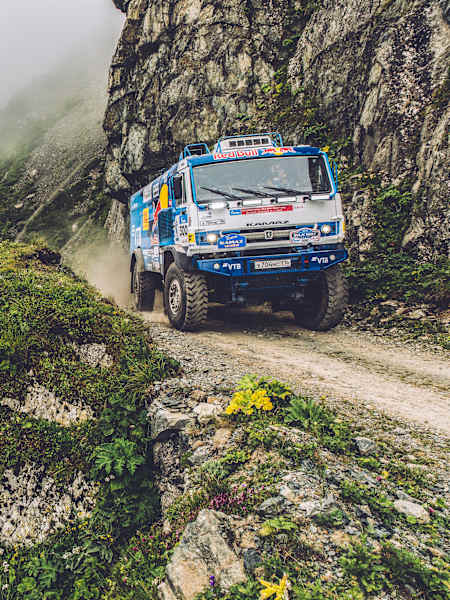 Una foto del camión Kamaz junto a un precipicio en una montaña.