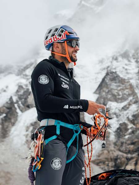 Andrzej Bargiel przygotowuje swój sprzęt do wspinaczki na lodospadzie Khumbu w Nepalu, na tle majestatycznego Mount Everestu.