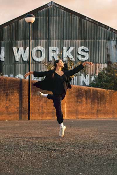 A dancer performs in front of a warehouse in London, England.