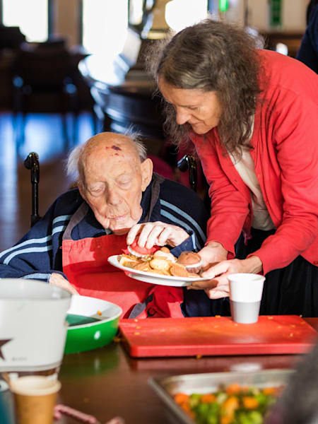 Una voluntaria ayuda a un anciano en Oma's Soep.