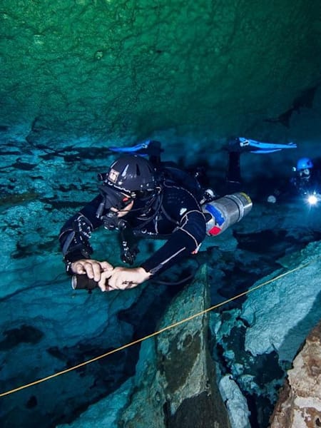A scuba diver goes through rocks during a dive at the Temple of Doom location in Tulum, Mexico.