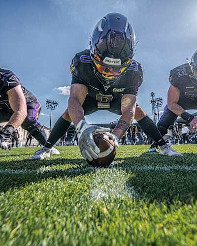 Five Vienna Vikings players crouch in a scrimmage line, one holding the ball
