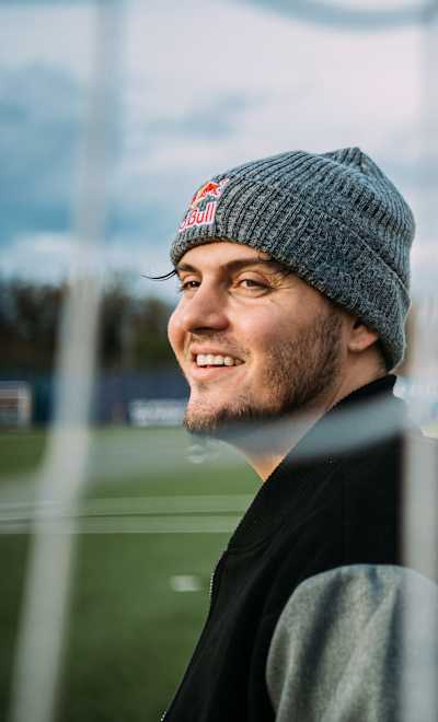 Mike LaBelle stands on the RB Leipzig pitch during an RBLZ media day in Leipzig, Germany, November 2022, wearing a Red Bull beanie.