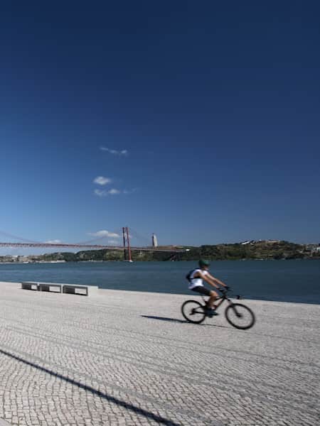 Cyclist riding a bike along river in Lisbon
