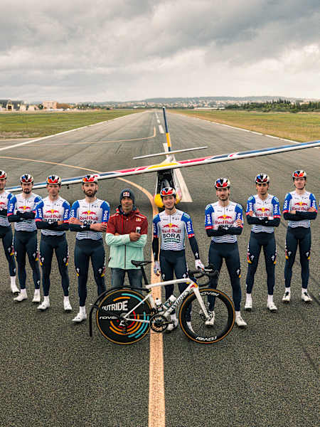Neun Fahrer von Red Bull - BORA - hansgrohe lassen ein Flugzeug fliegen.
