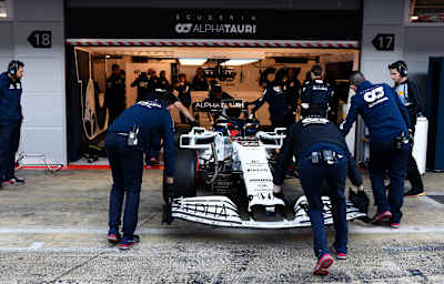 Teammitglieder schieben den AT01 in die Garage, beim Test in Barcelona 2020.