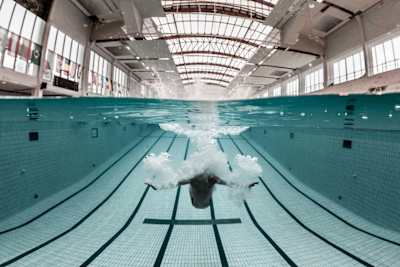 A high-diver slows down quickly underwater using their arms.