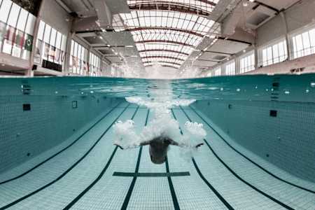 A high-diver slows down quickly underwater using their arms.