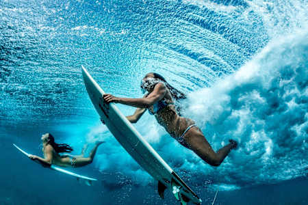 Keaulana (right) and her best friend, Maili Makana, dive under a wave en route to a surfing spot in Makaha.