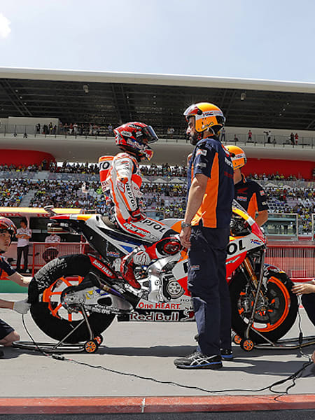 Marc Márquez espera a lomos de su Honda de MotoGP, mientras los mecánicos se disponen a quitar los calentadores de los neumáticos.
