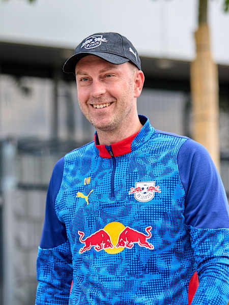 Ole Werner grinning while wearing a cap and RB Leipzig kit.