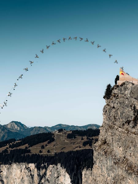 La légende du FMX Tom Pagès réalise un double frontflip à moto avant une éjection en BASE jump d'une rampe située sur une falaise à Avoriaz.