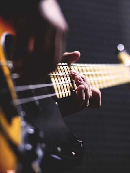 Plano de un hombre tocando las cuerdas de una guitarra eléctrica.