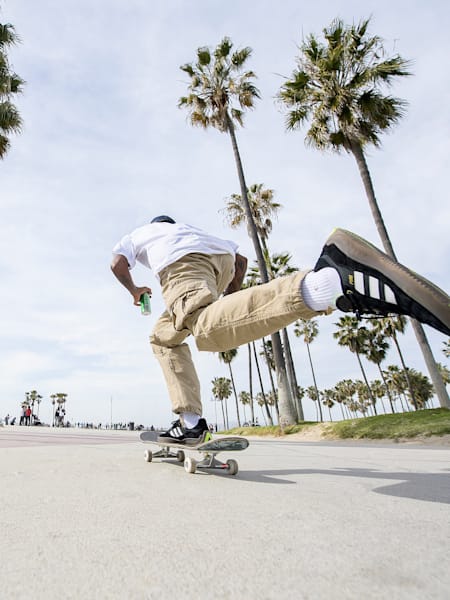 Felipe Gustavo auf dem Skateboard neben Palmen. 