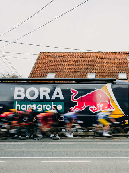 Red Bull - BORA - hansgrohe Fahrer, darunter Jordi Meeus und Laurence Pithie, fahren während der 78. Kuurne - Brussel - Kuurne in Belgien im März 2026 am kultigen Teambus vorbei