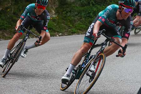 Ein Radprofi von BORA-hansgrohe lenkt in die Kurve ein.