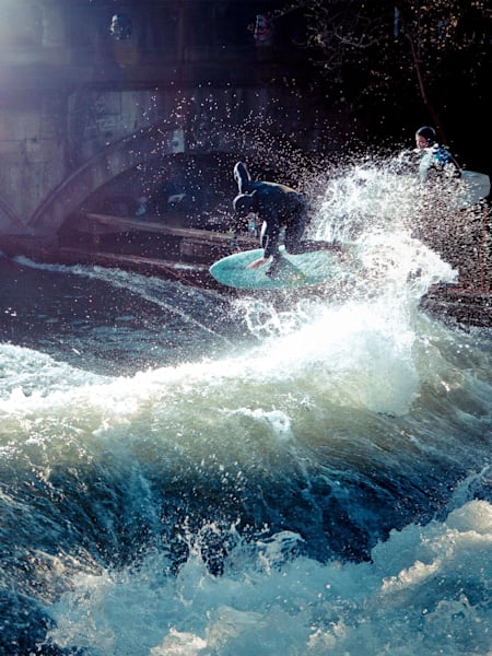 Eisbach-Legende Quirin Rohleder surft ein Eisbach in München und macht einen Backside Air.