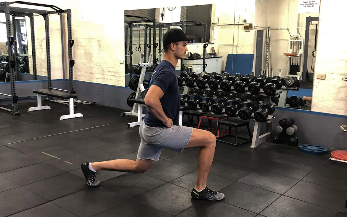 Un atleta realiza lunges en un gimnasio.