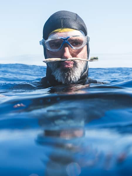 Ben Lecomte in una foto in posa nel mezzo del Pacifico con uno spazzolino trovato mentre nuotava