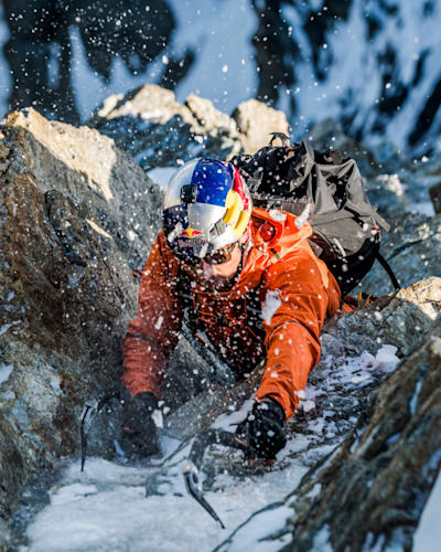 Mountaineer Nicolas Hojac climbing up a mountain rock face.