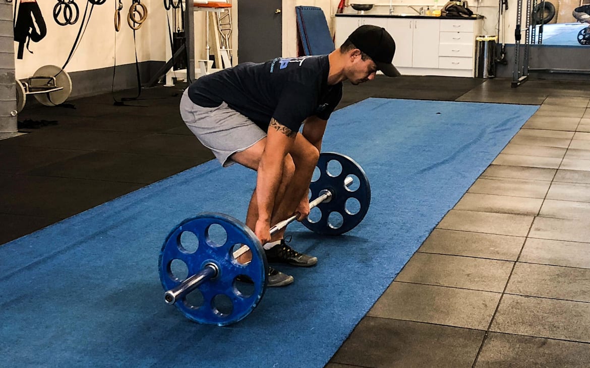 Un atleta trabaja con una barra con pesas.