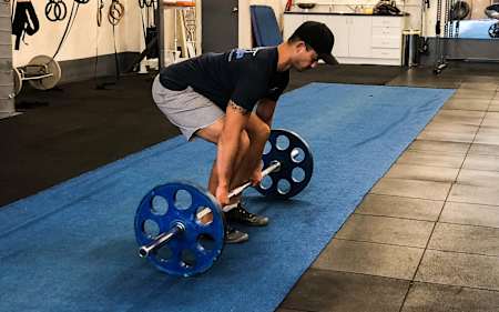 Un atleta trabaja con una barra con pesas.