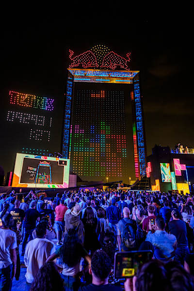 A vibrant crowd gathers beneath the Dubai night sky for the Red Bull Tetris World Final 2025, with illuminated blocks and the Red Bull logo creating a spectacular scene