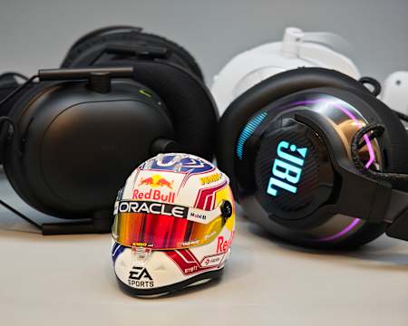 La imagen muestra una selección de auriculares para juegos actuales de JBL, Razer, Logitech e HyperX con un casco de Fórmula 1 en miniatura de Max Verstappen en primer plano.