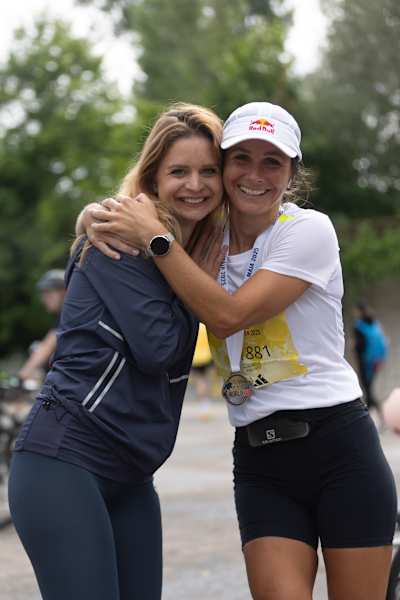 Zuzana Vráblová na zdjęciu obejmuje uczestnika po ukończeniu biegu Wings for Life World Run 2025 w Pieszczanach na Słowacji, dumnie nosząc czapkę Red Bull i medal ukończenia