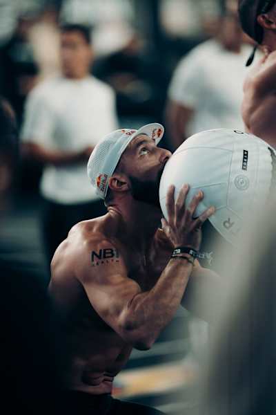 Alexander Rončević es captado en plena acción en HYROX Phoenix 2026 en Arizona, EE.UU., con una gorra de Red Bull y preparándose para lanzar una bola de muro.