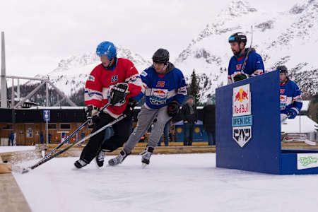 Eishockeyspielerinnen und Eishockeyspieler kämpfen während des elektrisierenden Red Bull Open Ice Events im verschneiten Arosa, Schweiz, am 30. November 2025 vor der Kulisse majestätischer Berge