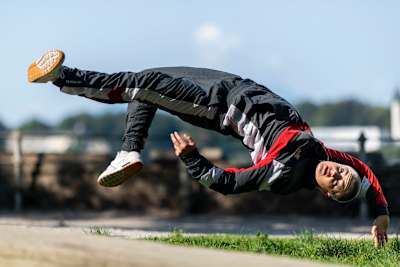 B-Girl Madmax is upside down in mid-air while performing a move.