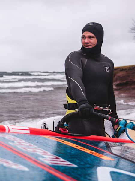 Windsurf-Weltmeister Philip Köster trägt sein Windsurf-Brett.