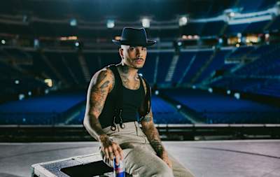 El artista de música y danza Rauw Alejandro se toma un respiro en el escenario con una lata de Red Bull.