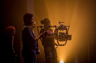 A cameraperson shoots during a video production in a studio.
