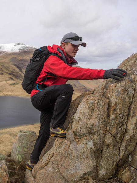 Man scrambles up rock face in Wales.