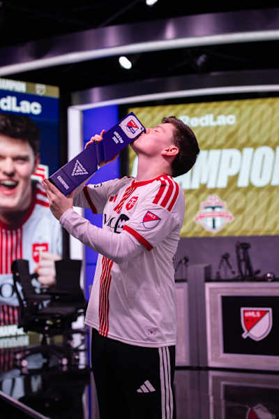 EA FC pro Alfie 'RedLac' Calder of RBLZ kisses the eMLS cup as he celebrates winning the 2026 title.