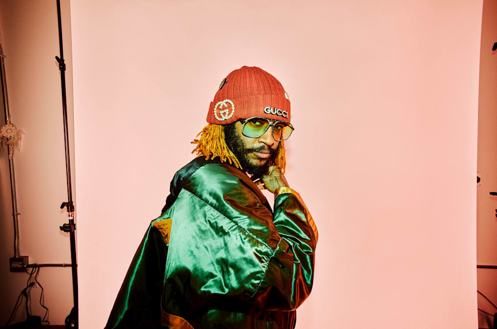 Thundercat wearing a custom-made backpack and Dragon Ball Z tee, glasses by Christian Roth, bracelets by IF & Co and a Bricks & Wood beanie adorned with Gucci brooches.