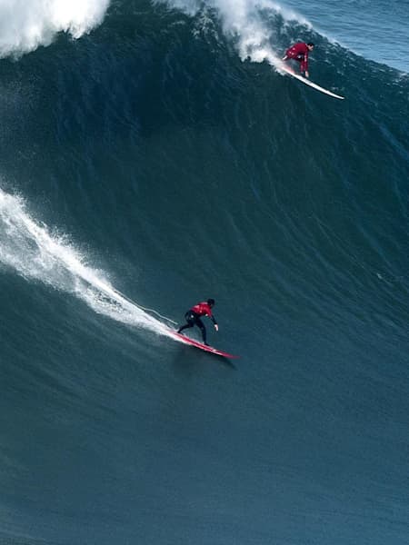 Dos surfers se meten en una enorme ola de izquierdas en Nazaré, Portugal