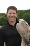 Steve Backshall posing with an gyrfalcon for a portrait.