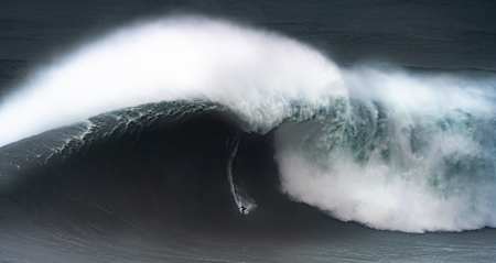 Le surfeur big wave Kai Lenny charge une très grosses vague pendant un session de surf de gros sur le spot de Nazaré au Portugal.